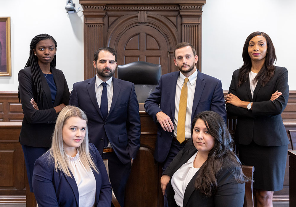 Law students posed in front of the judges bench in a courtroom. 
